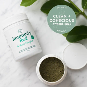 Container of 'Immunity Fuel' probiotic superfood with green powder on a marble surface, featuring 'Clean + Conscious Awards 2026' label.