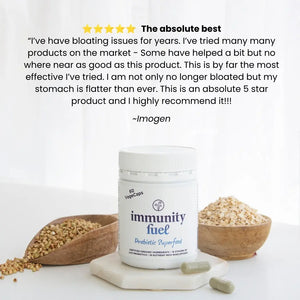 A white bottle labeled 'immunity fuel' stands on a small white tray between two wooden bowls of grains, with green capsules beside it. Above the product is a large customer review with a five-star graphic and the name Imogen.