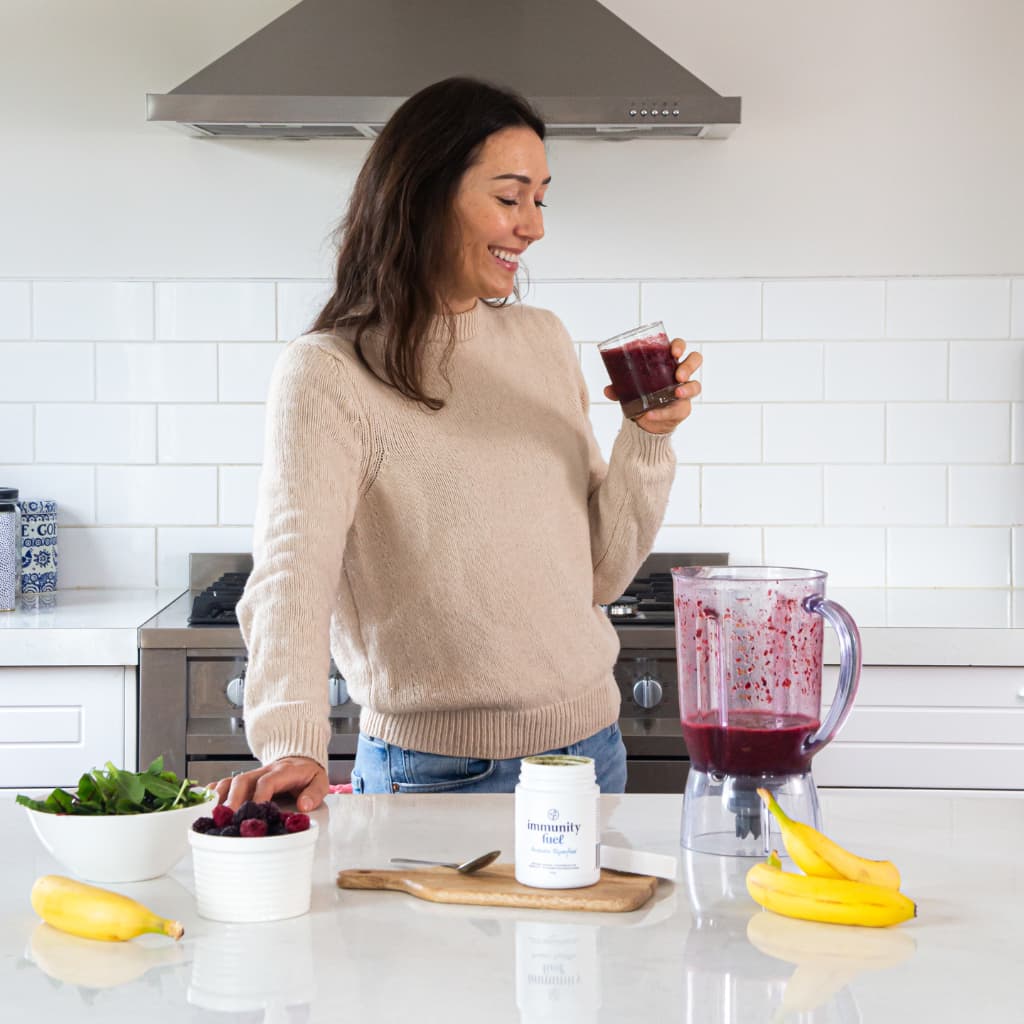 woman drinking berry smoothie with probiotic powder